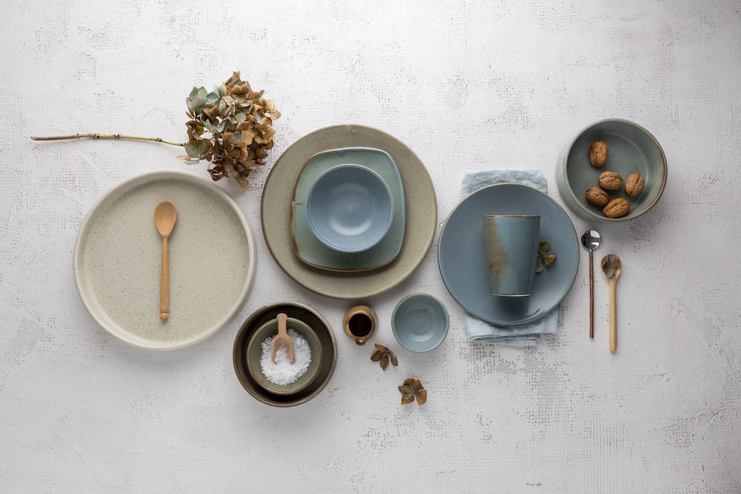 A selection of blue and beige earthy tones handmade pottery styled in a flat lay