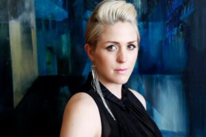 Website hero image example showing a lifestyle portrait of an artist in front of her own painting